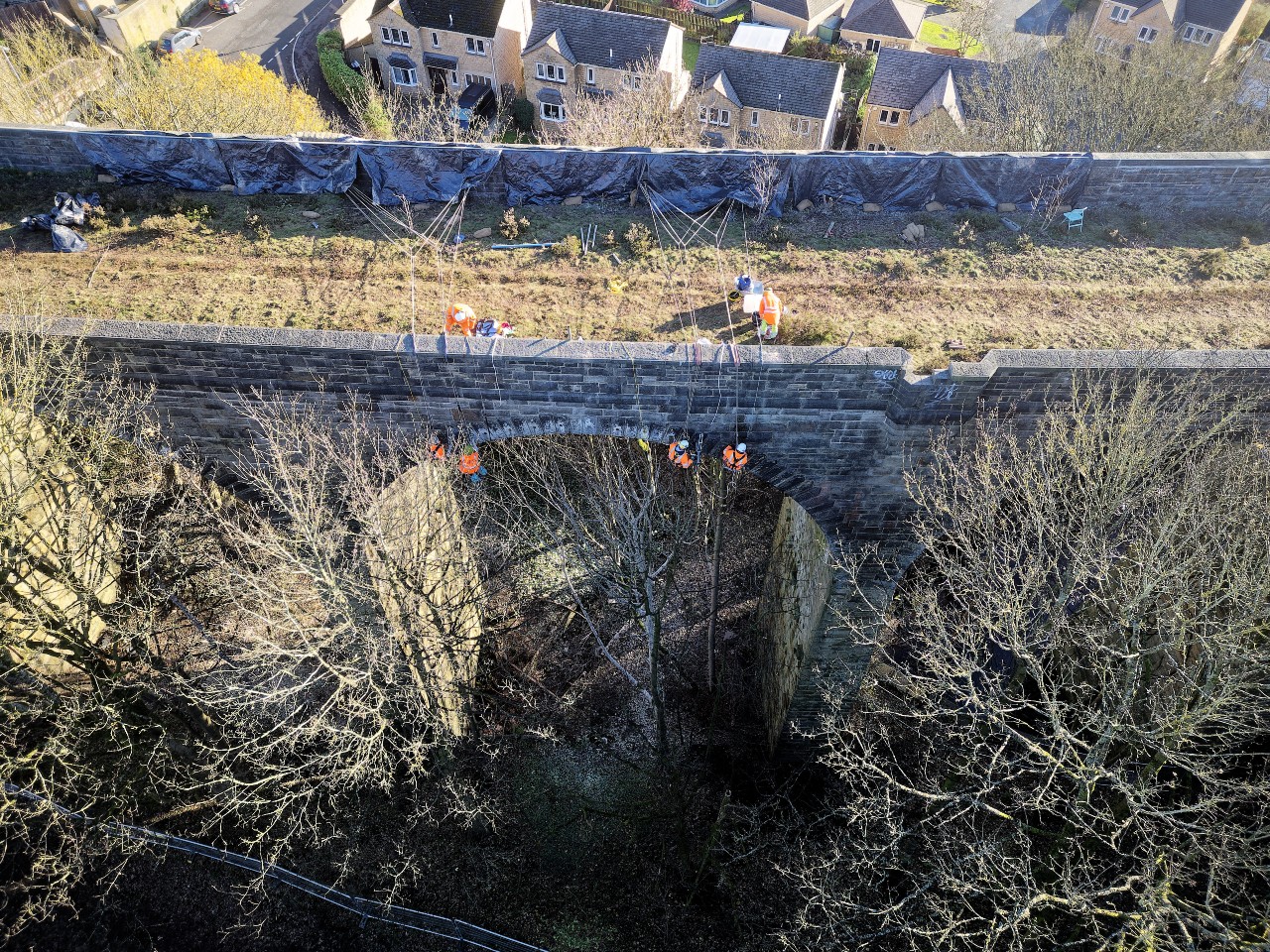 Rope access workers coring the voussoir stones in the arch.