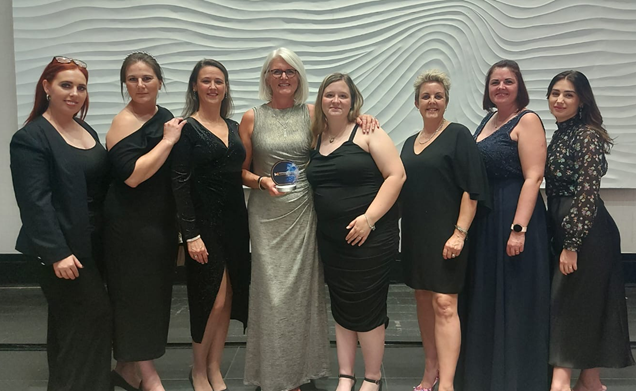 Eight ladies in evening dress accepting an award