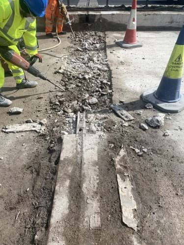 Roadworkers drilling out concrete during road repairs.