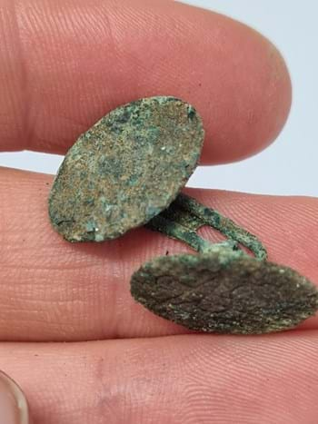 Old-looking copper-alloy cufflinks in a man's hand